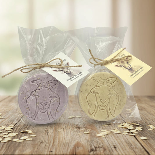 Two goat-shaped soaps in clear packaging with labels on a light gray background