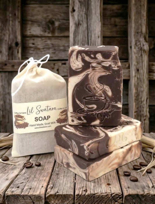 Sweet coffee goat milk tallow soap with engraved steaming coffee cup design, stacked on rustic barnwood beside coffee beans and muslin packaging.