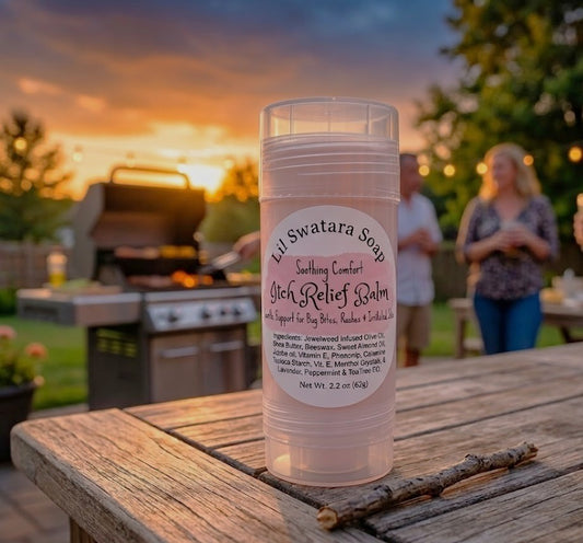 Woman in a soft floral dress applying itch relief balm to her forearm outdoors, with Lil Swatara Soap Itch Relief Balm sticks on a wooden table surrounded by wildflowers.