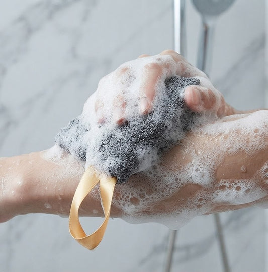 Handmade Oats, Milk & Honey soap tucked inside a grey textured exfoliating soap bag with a satin ribbon loop, displayed in a rustic country setting.