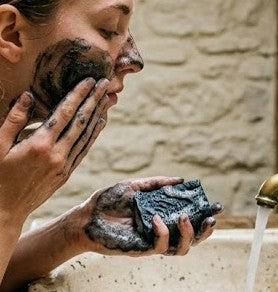 Girl washing face with charcoal tea tree goat milk tallow soap