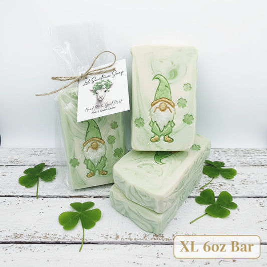 Handmade Aloe Clover goat milk soap bars with green gnome and clover design, one wrapped for gifting.
