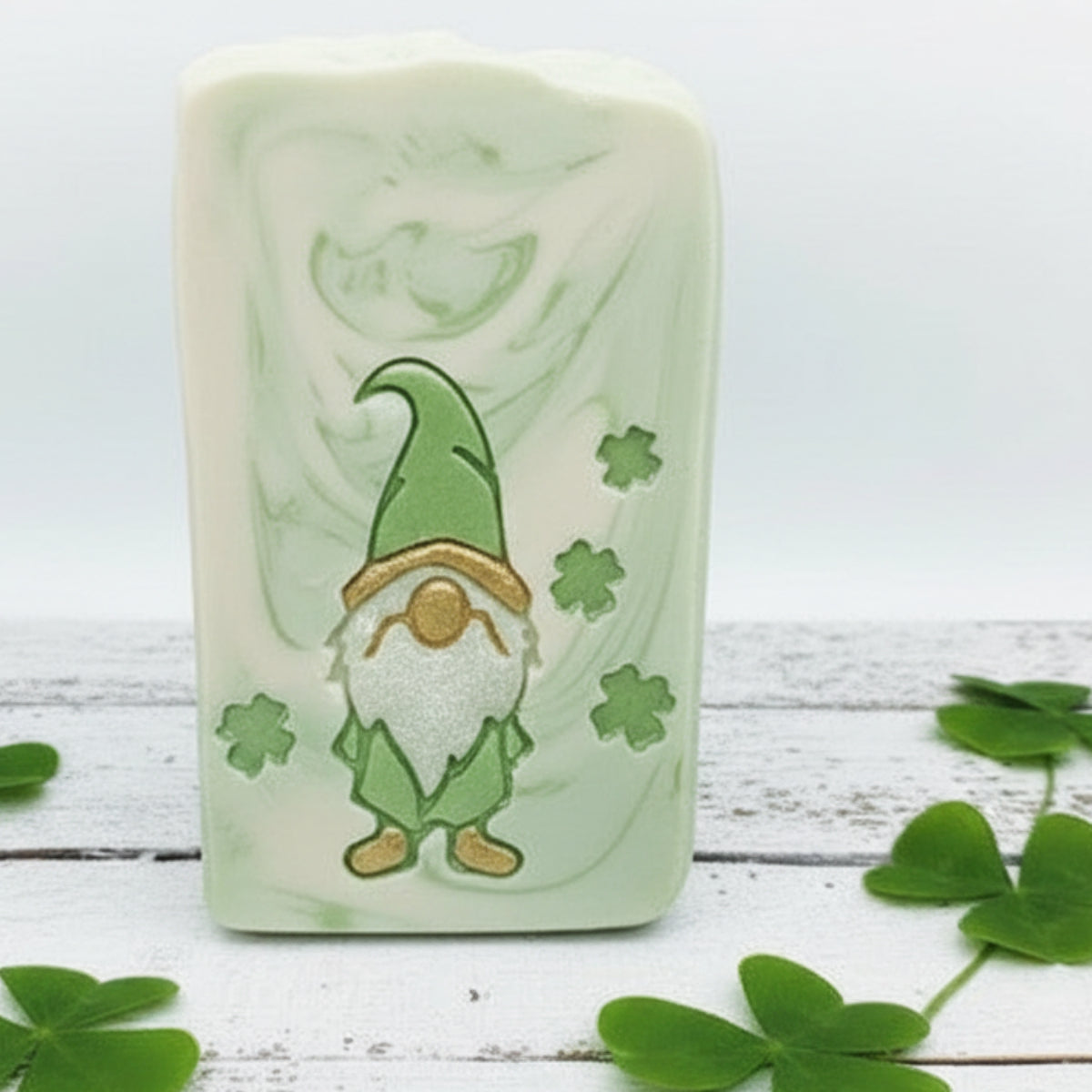 Three handmade soap bars with a St. Patrick's Day gnome design, including one wrapped in clear cellophane with a twine bow and a paper tag reading 'Lil' Santa Snow Shop' and 'Hand Made Soap Co!'.