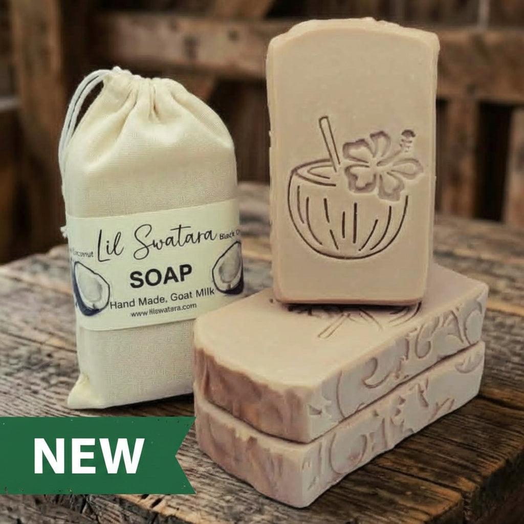 Black Coconut goat milk soap bar with engraved coconut drink design, shown beside its muslin sack packaging on rustic barnwood, handmade tallow blend XL 6oz bar.
