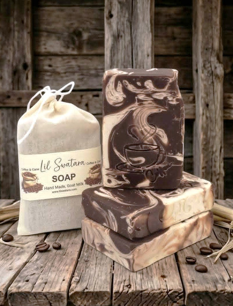 Sweet coffee goat milk tallow soap with engraved steaming coffee cup design, stacked on rustic barnwood beside coffee beans and muslin packaging.
