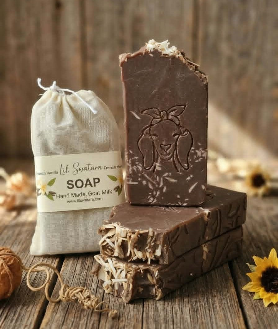 French Vanilla goat milk tallow soap XL 6oz bar with deep vanilla bean color, rustic shaved vanilla topping, and goat head stamp displayed on barnwood beside muslin packaging.
