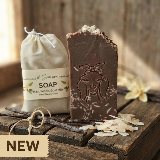 French Vanilla goat milk tallow soap XL 6oz bar with deep vanilla bean color, rustic shaved vanilla topping, and goat head stamp displayed on barnwood beside muslin packaging.
