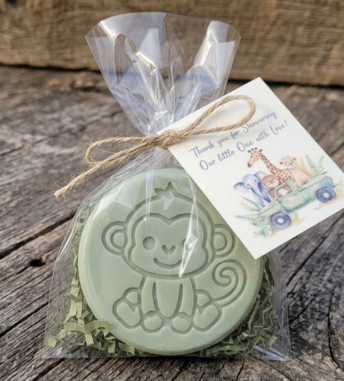 Handcrafted green monkey-embossed goat milk soap packaged in a clear cello bag with green crinkle shred, tied with a jute twine bow and a watercolor safari baby shower thank you tag.