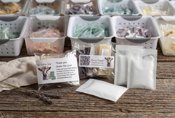 Handmade Lil Swatara Soap free sample packs displayed in baskets with individually wrapped soap sticks, lotion samples in white sealable bags, and branded goat milk soap pouches.