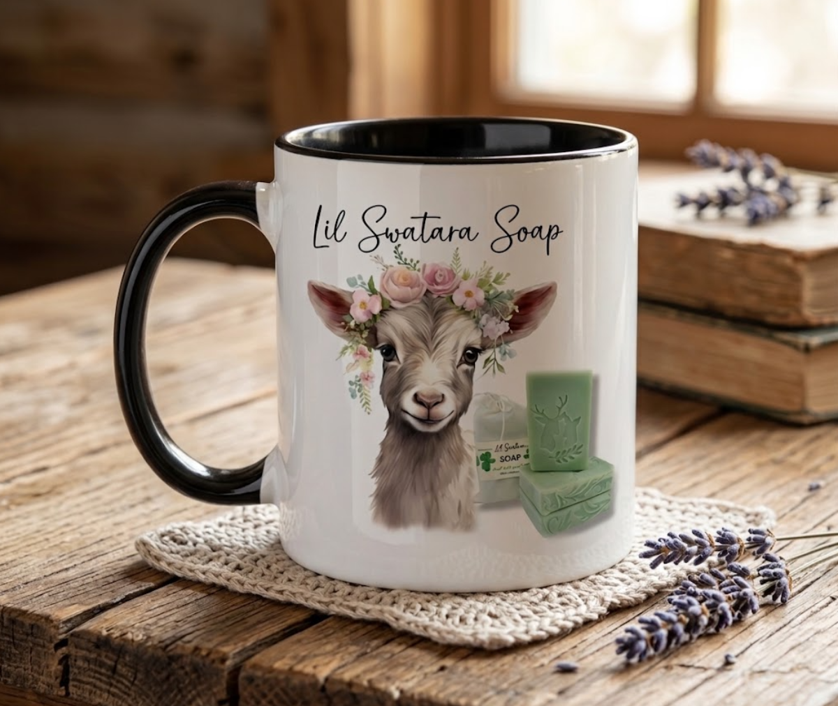 White ceramic mug with black accents featuring Lil Swatara Soap goat design on a crocheted coaster with artisan soap bars

