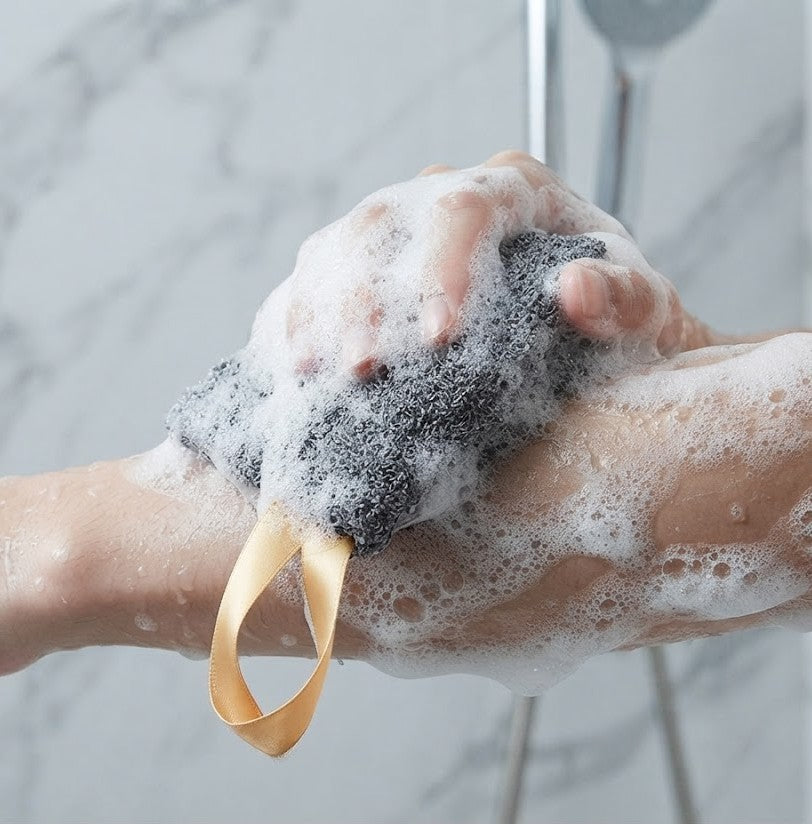 Handmade Oats, Milk & Honey soap tucked inside a grey textured exfoliating soap bag with a satin ribbon loop, displayed in a rustic country setting.