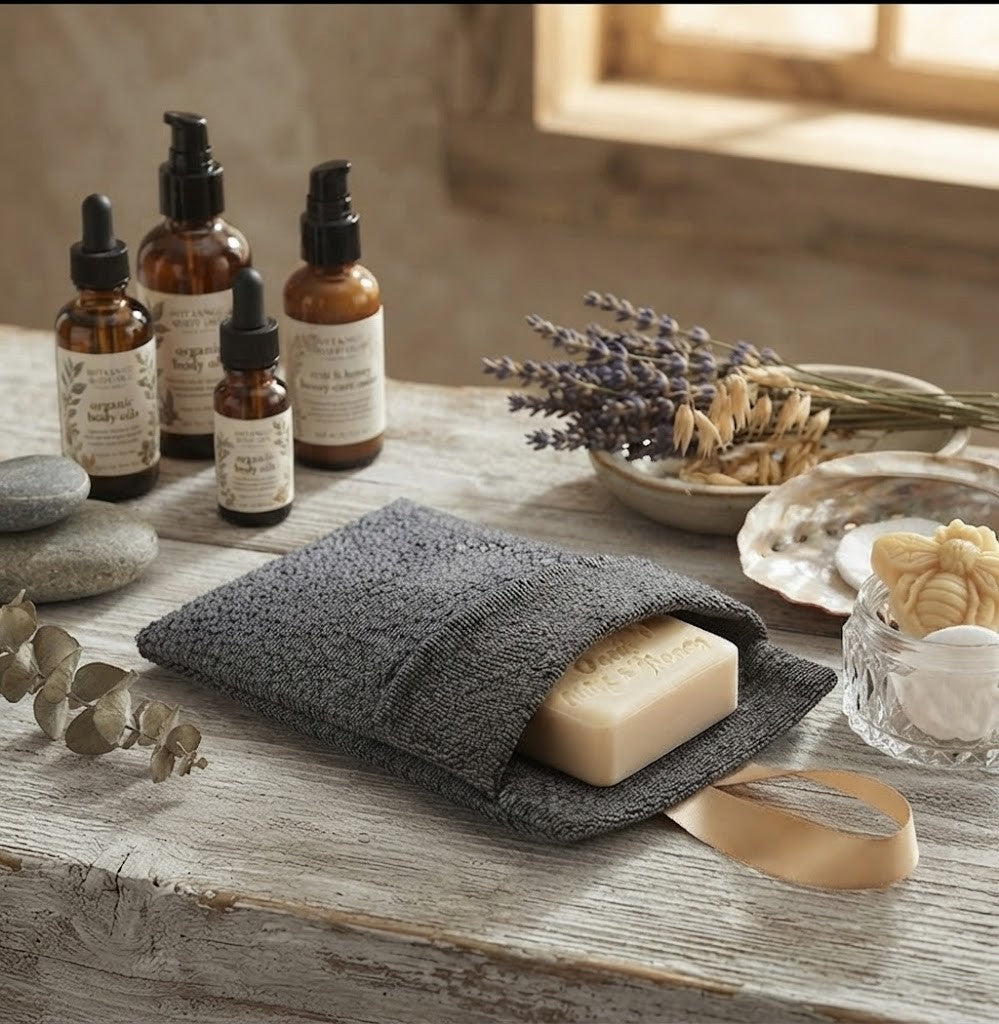 Handmade Oats, Milk & Honey soap tucked inside a grey textured exfoliating soap bag with a satin ribbon loop, displayed in a rustic country setting.