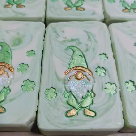 Handmade Aloe Clover goat milk soap bars with green gnome and clover design, one wrapped for gifting.