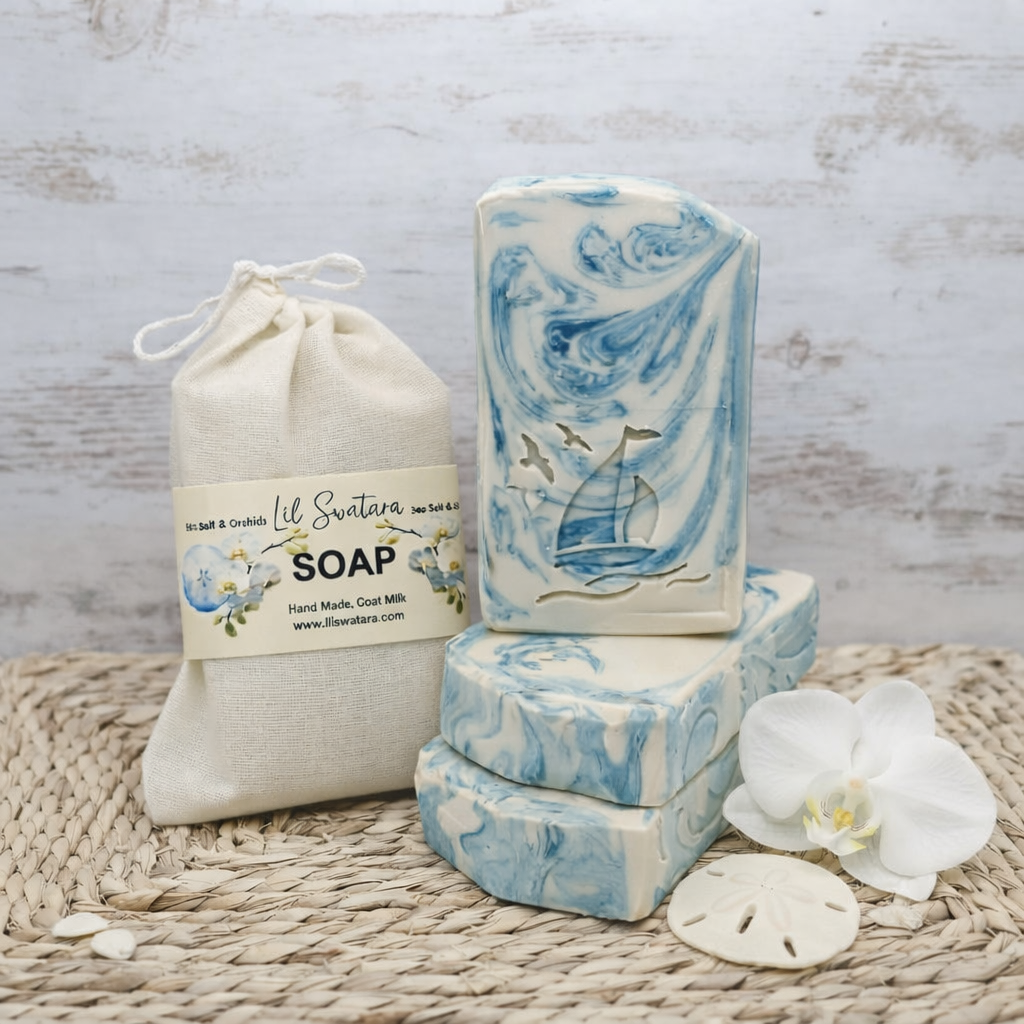 Sea Salt & Orchid tallow goat milk soap with creamy white base and teal swirls, sailboat stamp, orchid flower, and sand dollars on soft coastal beach with dunes and pale sky.