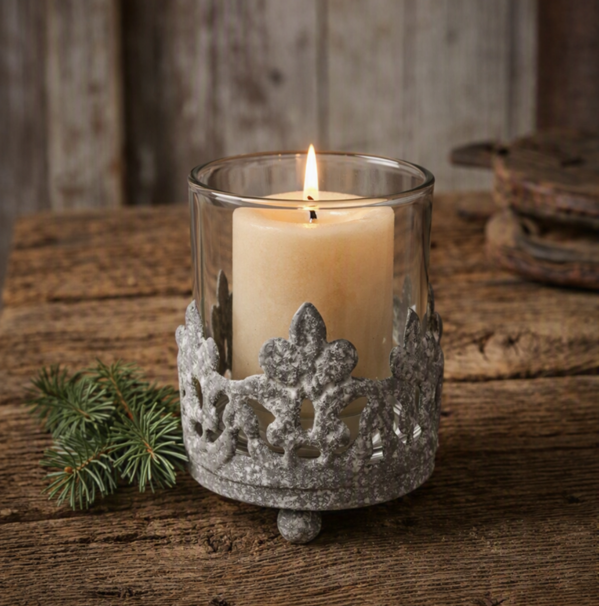 Vintage cast iron crown votive candle holder with clear glass insert on rustic wood table, candle not included.
