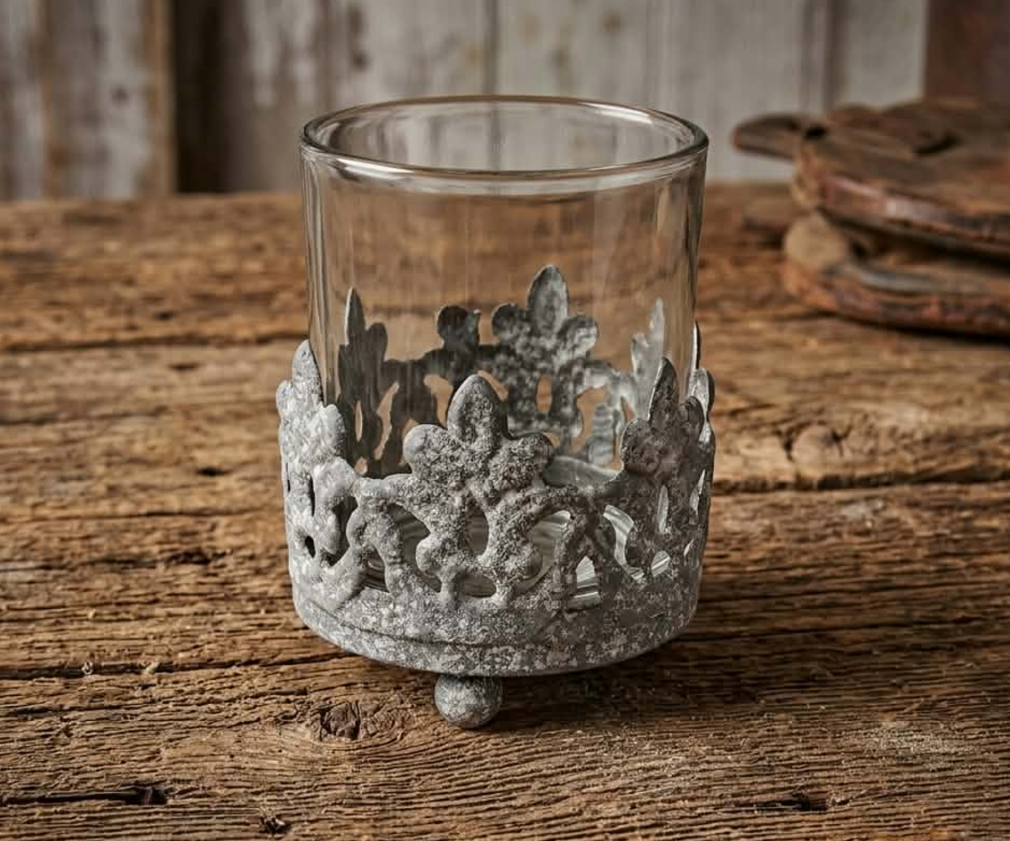Vintage cast iron crown votive candle holder with clear glass insert on rustic wood table, candle not included.
