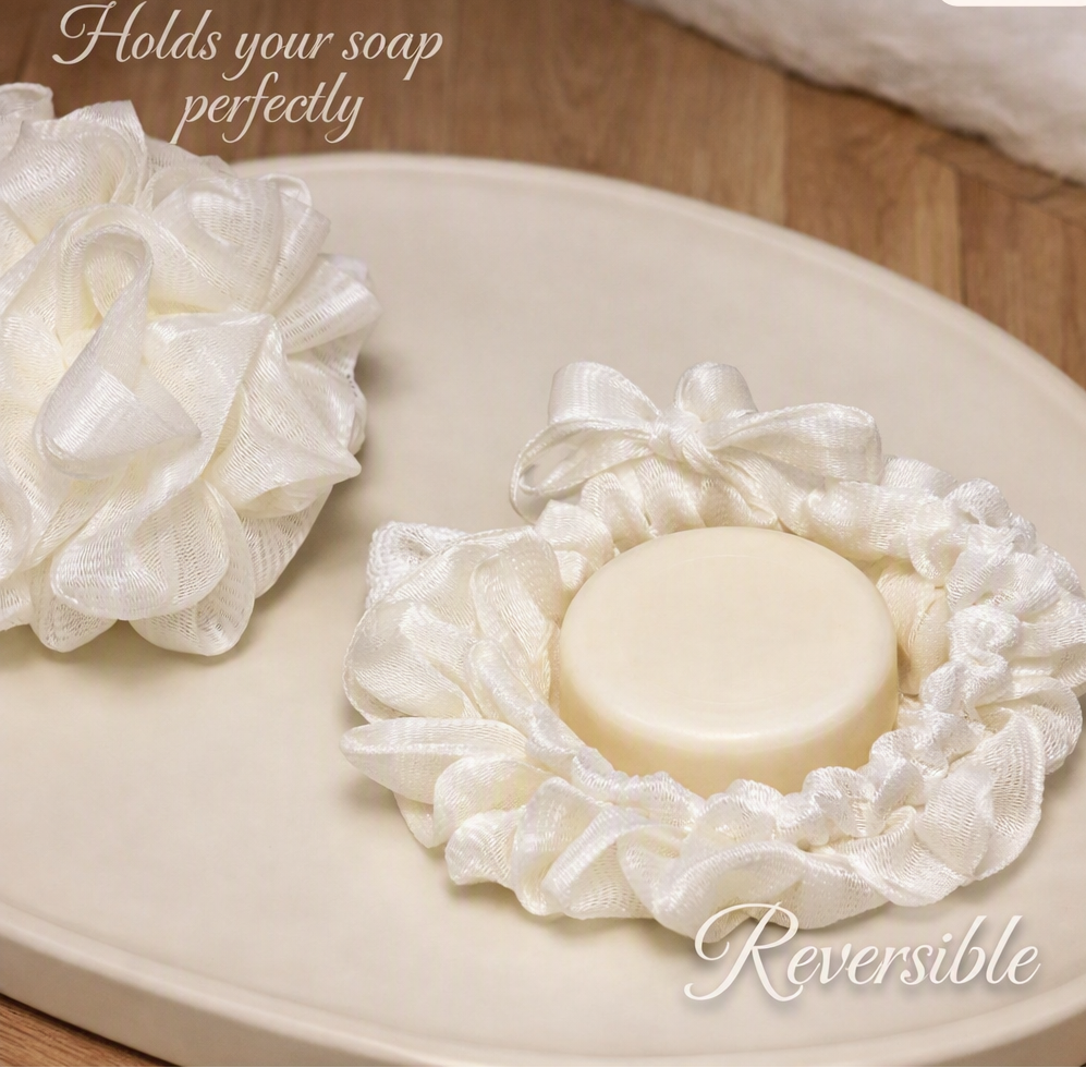 Dual‑sided soft wash ball with round goat milk soap puck inside a reversible drawstring pouch, shown on rustic wood for Lil Swatara Soap.