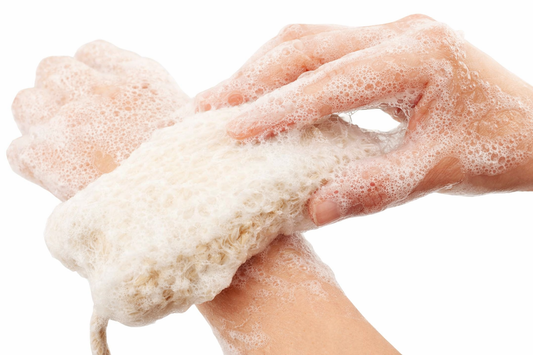 Close-up of hands scrubbing a natural sisal soap pouch covered in creamy white foam, showing clear texture and bright lighting against a white background.